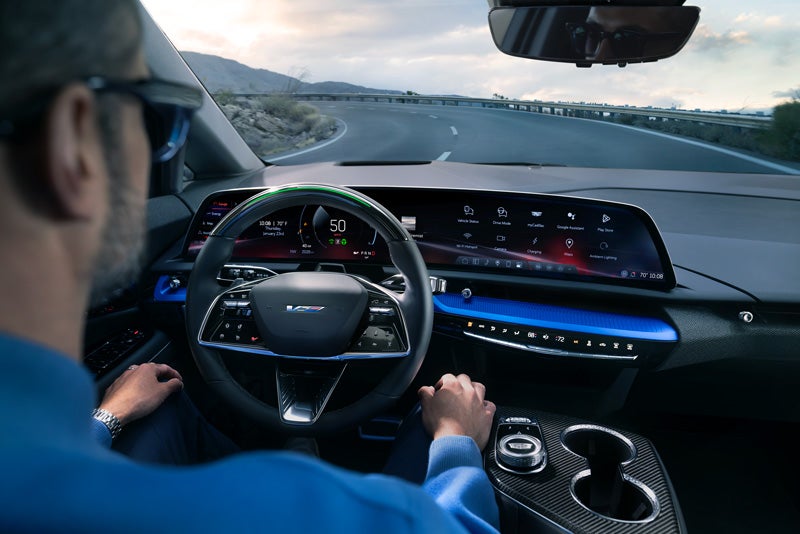 Front View of the 2026 OPTIQ-V Driving Through the Dusk Utilizing its Headlights | Cadillac of Bellevue in Bellevue WA
