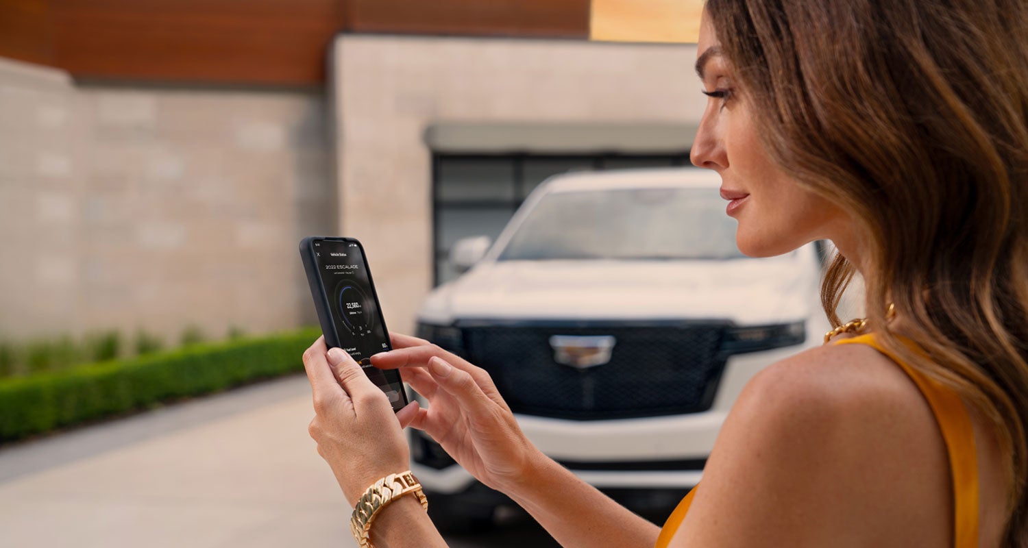 lady checking her mobile with a Cadillac vehicle background | Cadillac of Bellevue in Bellevue WA